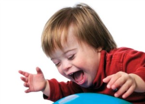 Child with Down Syndrome smiling and playing with ball isolated over a white background.